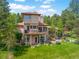 Expansive backyard with a deck, patio, lush landscaping, and a view of the house at 2398 Bitterroot Ln, Golden, CO 80401