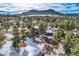 Aerial view of estate nestled among tall pine trees with mountain backdrop at 1298 Silverheels Dr, Larkspur, CO 80118