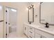 Bright bathroom featuring double sinks, white cabinets, dark hardware, and marble floors at 1298 Silverheels Dr, Larkspur, CO 80118