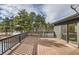 Large wooden deck with metal railing overlooks a serene wooded landscape through the sliding glass door at 1298 Silverheels Dr, Larkspur, CO 80118