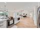 Open-concept kitchen with white cabinetry, stainless steel appliances, stone counters, and adjacent living areas at 1298 Silverheels Dr, Larkspur, CO 80118