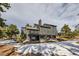 This is a two-story home with an elevated deck and wood siding in a forest setting with some snow on the ground at 1298 Silverheels Dr, Larkspur, CO 80118