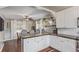 Bright eat-in kitchen with white cabinets, marble countertops, breakfast bar seating, and stylish open shelving at 134 S 5Th Ave, Brighton, CO 80601
