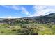 Scenic aerial view of a lush golf course nestled among unique red rock formations against a bright blue sky at 6874 Raspberry Run, Littleton, CO 80125