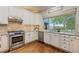 Charming kitchen with bright, white cabinets, stainless steel appliances and a picturesque window view at 6874 Raspberry Run, Littleton, CO 80125