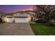 Charming home featuring a three car garage, brick accents, well-maintained landscaping, and a beautiful sky at dusk at 22778 E Alamo Ln, Aurora, CO 80015