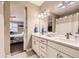 Bathroom with double sinks, white cabinetry, and access to the primary bedroom at 10555 Boston St, Commerce City, CO 80640