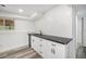 Basement wet bar featuring white cabinets, black countertops, and laminate flooring at 11172 W Exposition Dr, Denver, CO 80226