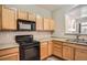Bright kitchen features black appliances, plenty of wood cabinets, and good light at 12711 Colorado Blvd # 607F, Thornton, CO 80241