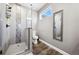 Bright bathroom featuring a walk-in shower with grey tile, a window, and wood-look floors at 156 Chapel Hill Cir, Brighton, CO 80601