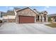 View of home featuring stone accents and a large driveway leading to a 2 car garage at 156 Chapel Hill Cir, Brighton, CO 80601