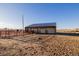 Wide shot of a barn with white siding and blue roofing that includes fencing and horse corrals at 35055 E Mississippi Ave, Watkins, CO 80137