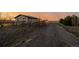 Charming single-story home showcasing the exterior with gravel driveway and rustic wooden fencing during sunset at 35055 E Mississippi Ave, Watkins, CO 80137