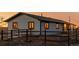 Detailed exterior of a single-story home featuring rustic wooden fencing and beautiful sunset light illuminating the windows at 35055 E Mississippi Ave, Watkins, CO 80137