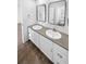 Modern bathroom featuring double sinks, mirrors, white cabinets, and neutral flooring at 950 Avena Ct, Elizabeth, CO 80107