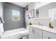 Modern bathroom featuring gray tiled walls, a shower-tub combo, and white vanity with modern fixtures at 6980 Niagara St, Commerce City, CO 80022