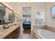 Bright bathroom featuring double vanity, tub, and neutral tile at 9382 Pike Way, Arvada, CO 80007