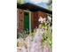 A green front door of a charming brick home with beautiful flowers in the front yard at 1695 S Beach Ct, Denver, CO 80219