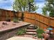 Landscaped backyard with a stone retaining wall, wood fence, and wooden steps, leading to a garden area at 2115 Coach House Loop, Castle Rock, CO 80109