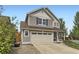 Attractive home with a beige two car garage, green lawn, mature trees, and covered porch with rocking chairs at 2115 Coach House Loop, Castle Rock, CO 80109