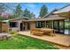 Outdoor space featuring a wooden deck with table and benches, manicured lawn, and backyard patio at 182 Ridge Rd, Boulder, CO 80303