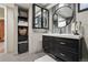 Modern bathroom with a black vanity, striking round mirror, decorative tile and ample storage at 6948 Buckskin Dr, Littleton, CO 80125