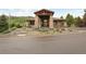 Attractive clubhouse entrance with stone pillars and wood beam canopy with manicured landscaping and asphalt drive at 6948 Buckskin Dr, Littleton, CO 80125