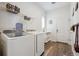 Well-lit laundry room with modern washer and dryer, overhead shelving, and wood-look flooring at 4422 Mt Shavano St, Brighton, CO 80601