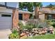 Inviting front entrance with brick facade, stone accents, vibrant flowers, and well-manicured landscaping at 12651 E Bates Cir, Aurora, CO 80014
