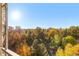 Balcony view showcasing treetop foliage and residential buildings beneath a bright sky at 1200 N Humboldt St # 1003, Denver, CO 80218