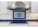 Close-up of the cooktop featuring custom tile backsplash and stainless steel vent hood at 1200 N Humboldt St # 1003, Denver, CO 80218