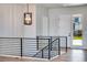 Bright upper hallway with modern railing, hardwood floors and entry door at 14408 Hop Clover Trl, Parker, CO 80134