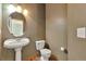 Elegant half-bathroom with a pedestal sink, toilet, and decorative mirror creating a charming space at 14825 Almstead St, Hudson, CO 80642