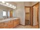Bright bathroom featuring double sinks, wooden cabinetry, and a large mirror, offering ample space at 14825 Almstead St, Hudson, CO 80642