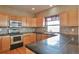 Well-lit kitchen with wood cabinets, stainless steel appliances, and black countertops, offering a functional cooking space at 14825 Almstead St, Hudson, CO 80642