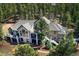 An aerial view of a large stucco home with a gray roof surrounded by tall pine trees and a deck with furniture at 26806 Evergreen Springs Rd, Evergreen, CO 80439