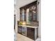 Elegant wet bar featuring custom cabinets, glass doors, granite countertops, and a built-in wine cooler at 26806 Evergreen Springs Rd, Evergreen, CO 80439