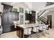 Bright, spacious kitchen with dark cabinets, large island with barstool seating, and views of staircase at 26806 Evergreen Springs Rd, Evergreen, CO 80439