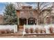 Charming two-story brick home with a covered porch and white picket fence at 1614 Gaylord St, Denver, CO 80206