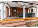 Covered front porch with brick pillars, cozy seating, and an outdoor rug at 1614 Gaylord St, Denver, CO 80206