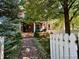 Charming brick home with a lush front yard, mature trees, and a classic white picket fence at 1614 Gaylord St, Denver, CO 80206