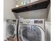 Modern laundry room with front load washer and dryer and upper dark wood shelf at 2785 S Lisbon Way, Aurora, CO 80013
