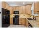 Spacious kitchen featuring wooden cabinets, granite countertops, tile backsplash, and black appliances at 5612 S Jebel Way, Centennial, CO 80015