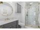 Modern bathroom featuring marble shower, gray vanity with gold fixtures, and round mirror at 14533 W 3Rd Ave, Golden, CO 80401