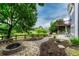 Serene backyard featuring a stone fire pit, brick walkway, and tiered patio spaces near wooded open space at 4688 Cedar Glen Pl, Castle Rock, CO 80109