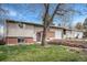 Charming split-level home featuring a brick facade, well-maintained lawn, and a quaint front garden at 10983 W Exposition Pl, Lakewood, CO 80226