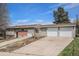 Home with a multi-car garage, brick accents, and a front yard with mature trees under a bright blue sky at 10983 W Exposition Pl, Lakewood, CO 80226