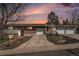 Inviting ranch-style home showcasing a brick facade, well-kept lawn, mature tree, and driveways leading to attached garages at 10983 W Exposition Pl, Lakewood, CO 80226