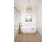 A soaking tub with marble-tiled walls and a modern gold faucet, lit by an elegant chandelier at 3022 Fenton St, Wheat Ridge, CO 80214