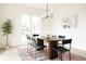 Bright dining room features a custom wood table on a patterned rug, large window and tree at 3022 Fenton St, Wheat Ridge, CO 80214